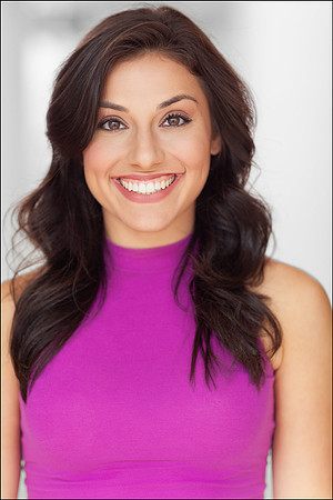 Actor headshot of young woman in magenta top, NYC studio portrait with confident and warm expression.
