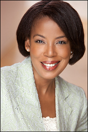 Black woman in a light green jacket smiling in a clean, professional headshot.