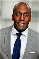Black man in a gray suit and blue tie photographed in a clean, professional NYC headshot.