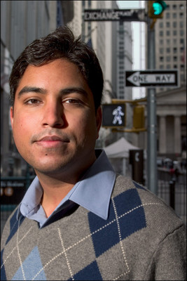 Outdoor headshot of a man in sweater standing near Wall Street and Exchange Place signs, photographed for a magazine cover in NYC.