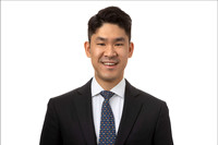 Headshot of man in dark suit on white seamless backdrop.