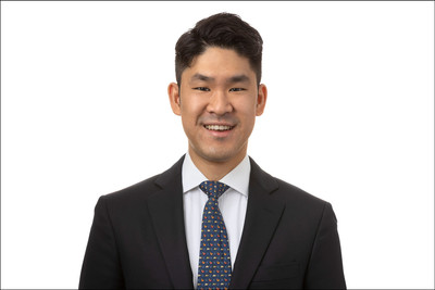 Headshot of man in dark suit on white seamless backdrop.