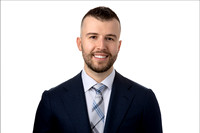Headshot of man in blue suit on white seamless background.