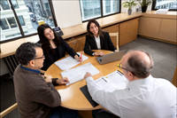 Corporate team seated at a round table in discussion during an on-location headshot session.