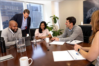 Team of professionals in a corporate NYC office engaged in a meeting around a conference table.