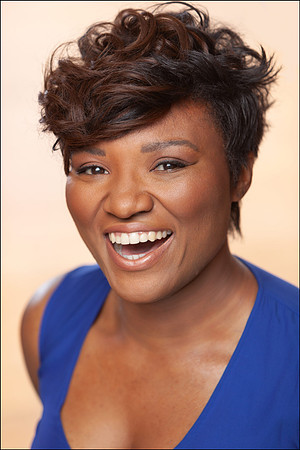 Professional NYC commercial headshot of Black woman in blue top, smiling and full of personality.