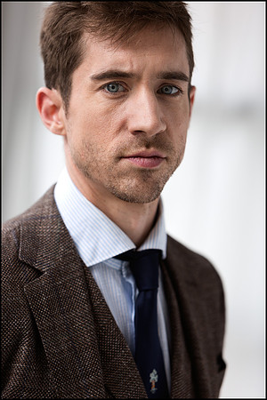 NYC character headshot of young man in suit, serious and focused expression